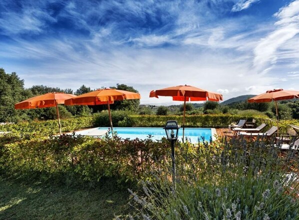 Un área de piscina con sombrillas naranjas, sillas de descanso y un farol.