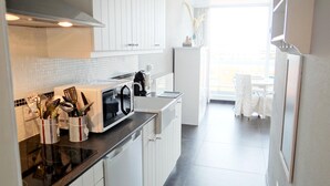 Eine moderne Küche mit weißen Schränken, einer schwarzen Arbeitsplatte und einer Kaffeemaschine.
