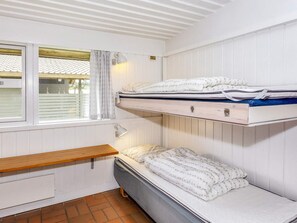 Une chambre de dortoir avec des lits superposés, une fenêtre avec des rideaux et une table de chevet.