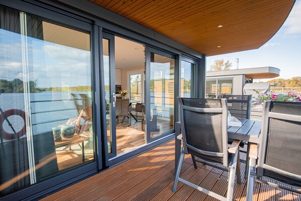 Une terrasse extérieure moderne, dotée de portes vitrées donnant sur un espace intérieur, et comprenant une table et des chaises.
