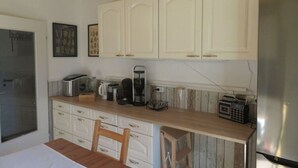 Une cuisine avec des meubles blancs, un plan de travail en bois, un réfrigérateur et une radio.