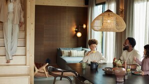 A modern interior with a wooden staircase, a dining area with a table, chairs, and a hanging light fixture. - Luxury Villa in Drenthe With Outdoor Spa (Appelscha)