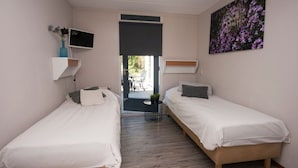 Un dormitorio con dos camas individuales, un televisor en la pared y un cuadro de flores.