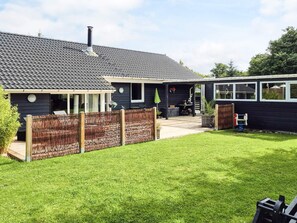 A house with a tiled roof, a covered patio, and a fenced backyard.