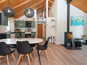 Une cuisine moderne avec des meubles en bois, un coin repas comprenant une table et des chaises, et un poêle à bois.