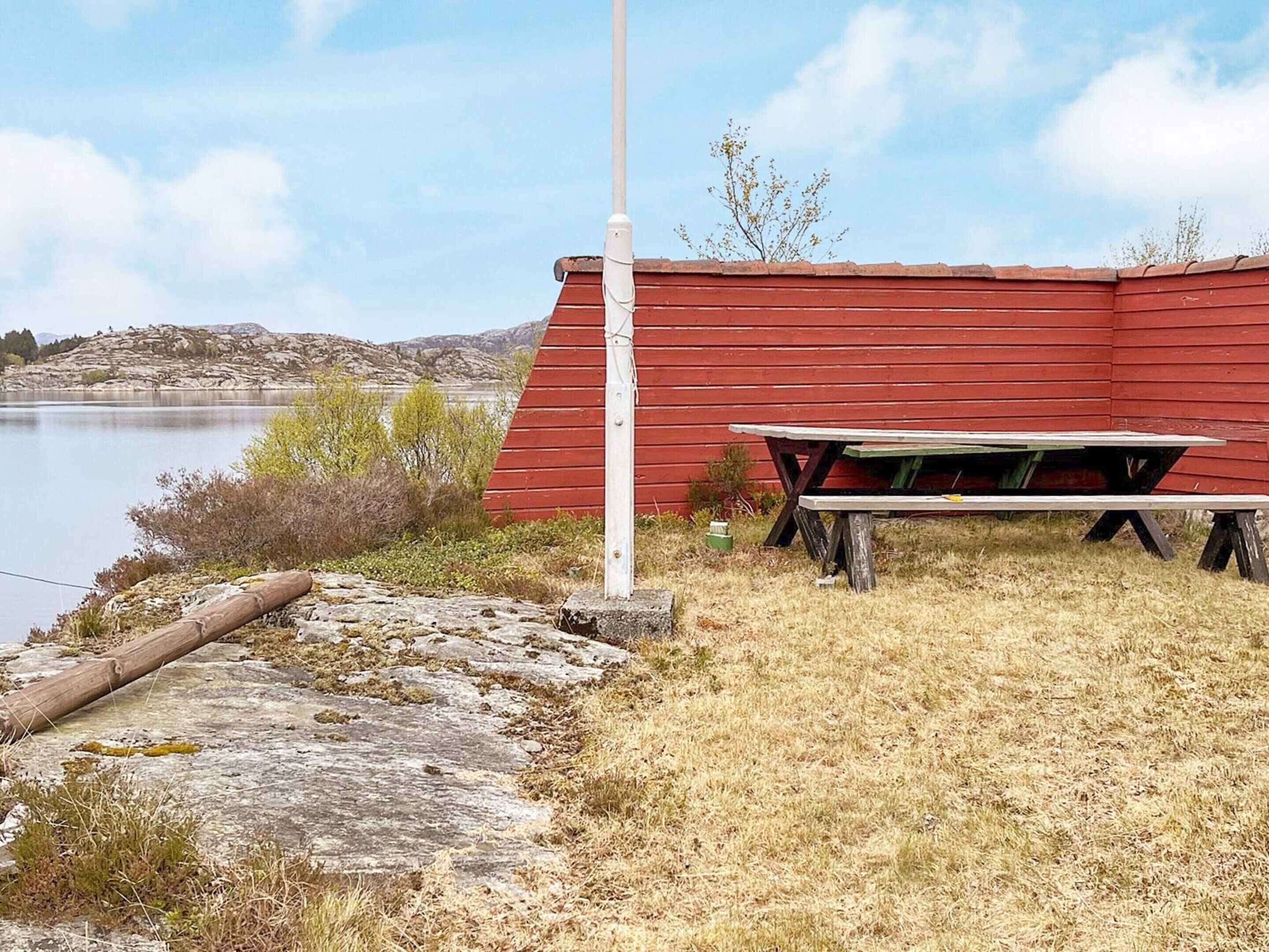 Una estructura de madera roja con una mesa de picnic y un asta de bandera.