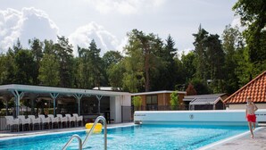 A swimming pool with a lifeguard stand, lounge chairs, and a covered seating area. - Modern House With Roof in Rhenen (Rhenen)