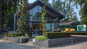 A modern building with large glass windows, a stone wall, and a signboard. - Modern House With Roof in Rhenen (Rhenen)