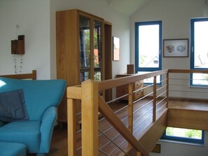 A room with a blue sofa, wooden staircase, and a bookshelf. - Engemann Modern Retreat (Kassel)