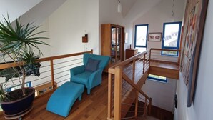 A loft-style room with a wooden staircase, a blue sofa, and a potted plant. - Engemann Modern Retreat (Kassel)