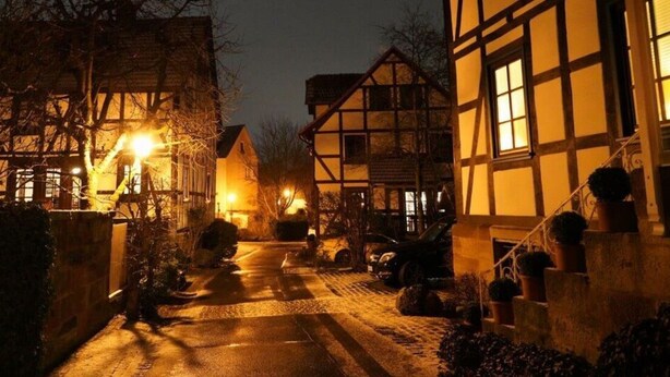 A narrow street lined with traditional half-timbered houses, illuminated by warm street lamps. - Engemann Modern Retreat (Kassel)