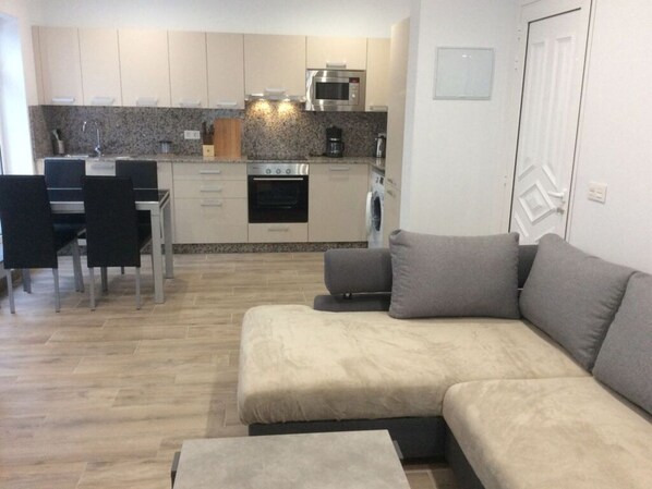 Una cocina moderna con encimeras de granito, electrodomésticos de acero inoxidable y un comedor con una mesa y sillas negras.