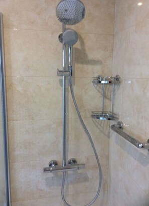 A shower with a handheld showerhead and a wall-mounted faucet.