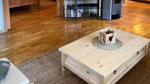 Una sala de estar con piso de madera, un mueble para televisión, una chimenea y un sofá.