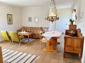 A cozy living room with a sofa, chairs, a dining table, and a chandelier.