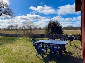 Eine Terrasse mit Tisch, Stühlen, einer Steinmauer und einem Grill.