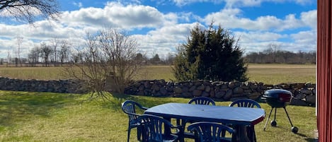 An outdoor patio with a table and chairs, a stone wall, and a grill.