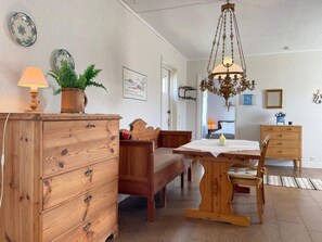 Una stanza accogliente con un comò in legno, una panca, un tavolo con una candela e un lampadario.