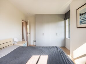 A bedroom with a bed, bedside table, lamp, wardrobe, and a window with a view. - Villa in St-idesbald Near the Sea (Koksijde)