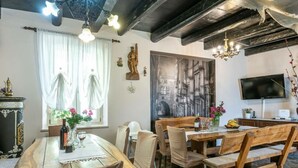 A dining area with a wooden table and chairs, a chandelier, and a large painting on the wall. - Nada Comfortable Holiday Residence (Vodnjan)