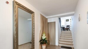 A hallway with a large ornate mirror, a potted plant, and a staircase leading to another room. - Nada Comfortable Holiday Residence (Vodnjan)