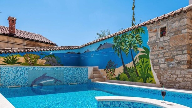 A swimming pool with a mosaic tile design, a stone wall, and a mural depicting a tropical scene. - Nada Comfortable Holiday Residence (Vodnjan)