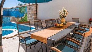 A dining area with a table, chairs, and a large umbrella. - Nada Comfortable Holiday Residence (Vodnjan)