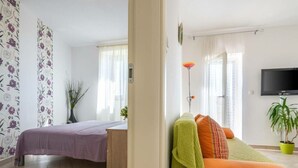 A hotel room with a bed, a sofa, a TV, and a window with curtains. - Nada Comfortable Holiday Residence (Vodnjan)