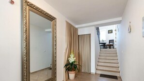 A hallway with a large ornate mirror, a potted plant, and a staircase leading to another room.