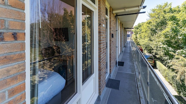 A covered balcony with a view of a tree-lined street. - Coastal Escape w/ Sauna (Zoutelande)