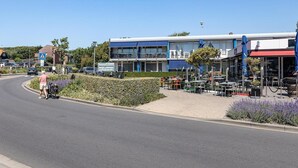 A building with a blue and white facade, outdoor seating area, and a pedestrian pathway. - Coastal Escape w/ Sauna (Zoutelande)
