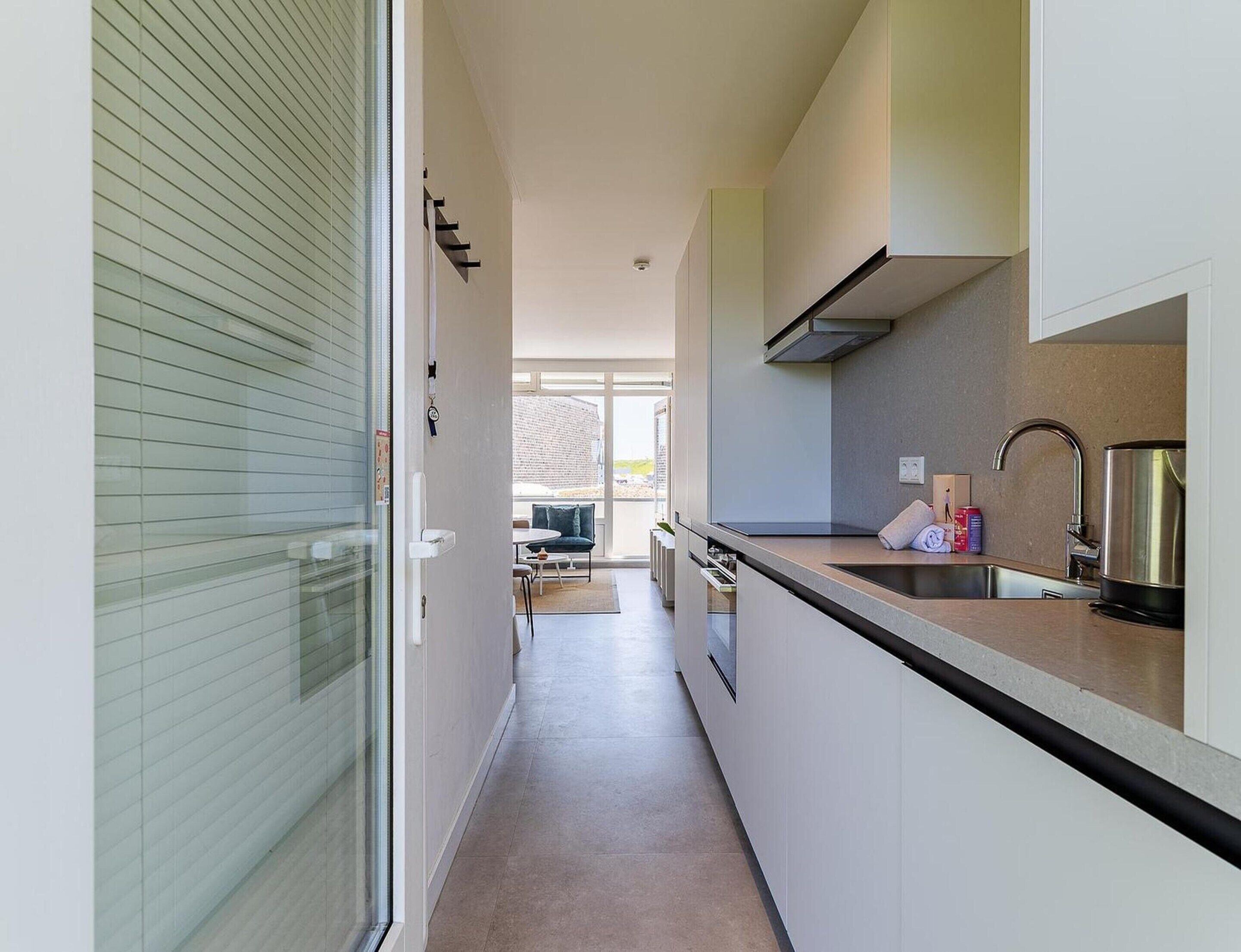 A narrow kitchen with a countertop, a sink, and a stove.