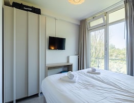 A hotel room with a bed, a TV mounted on the wall, and a window with curtains.
