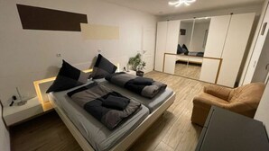 A modern bedroom with a bed, bedside table, and a mirror. - Nice Apartment in Himmelkron (Himmelkron)