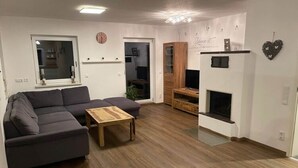 A modern living room with a sectional sofa, a wooden coffee table, a fireplace, and a television. - Nice Apartment in Himmelkron (Himmelkron)
