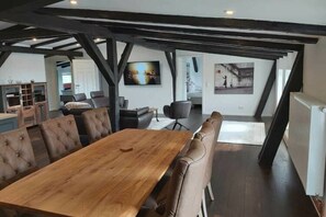 A spacious loft with a large wooden dining table, leather chairs, and exposed wooden beams. - Holiday Apartment in Klein Upahl (Klein Upahl)