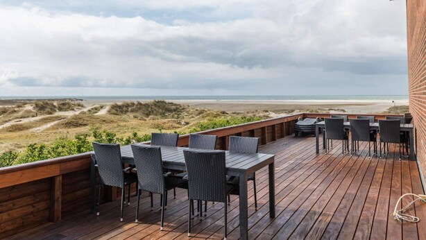 A wooden deck with outdoor furniture overlooking a beach and dunes. - 4 Person Holiday Home in Fano (Fano)