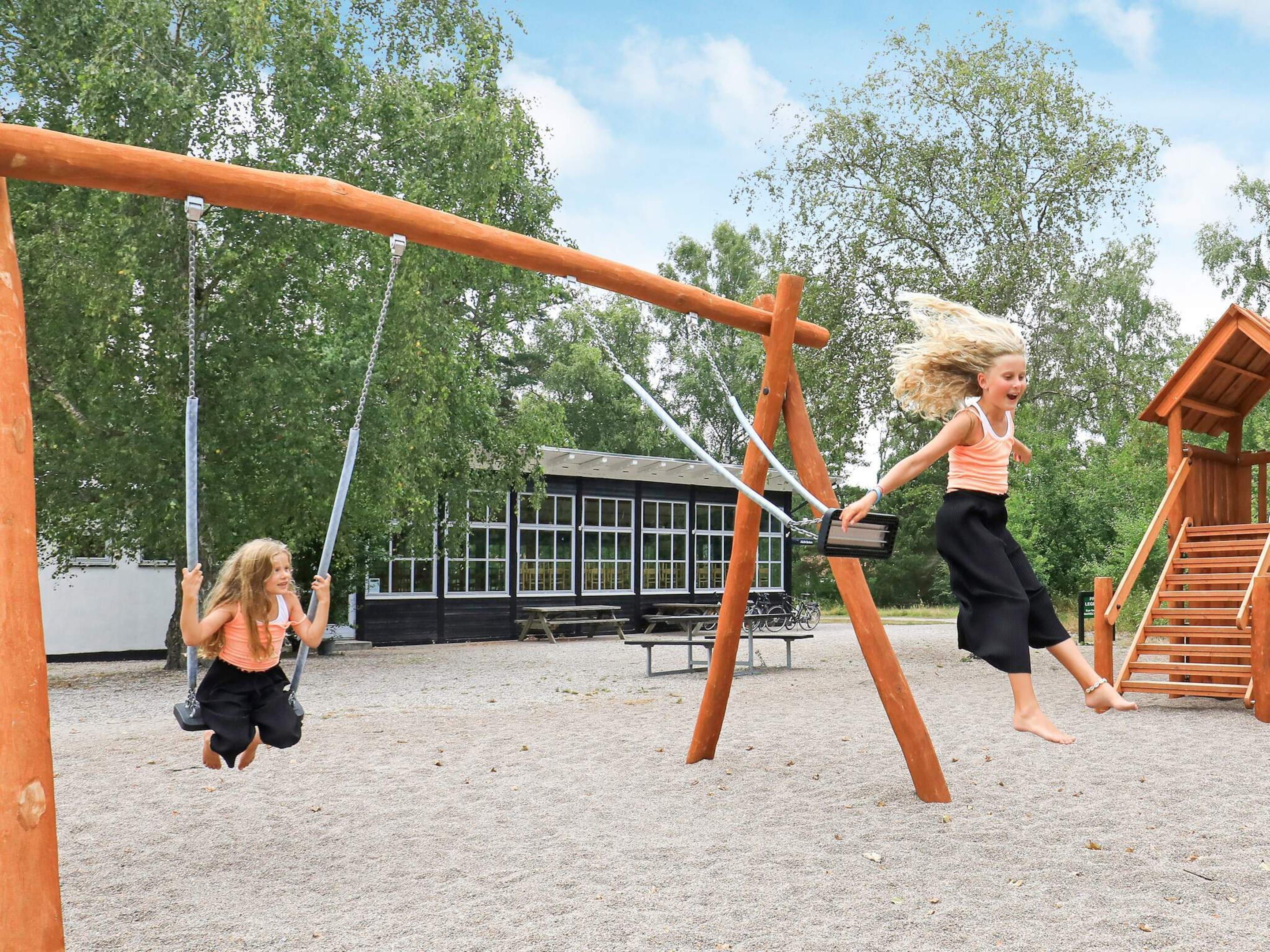 Ein Spielplatz mit Schaukeln und einer Holz-Kletterkonstruktion.