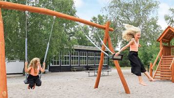Ein Spielplatz mit Schaukeln und einer Holz-Kletterkonstruktion.