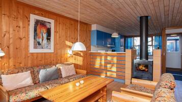 A cozy wooden interior with a sofa, a wooden table, and a fireplace.