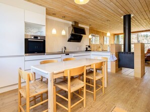 Una cocina moderna con una mesa y sillas de madera, un horno Bosch y una estufa negra.
