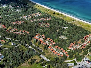 An aerial view of a coastal residential area with clusters of houses surrounded by dense forests, a beach, and a clear blue sea. - 6 Person Holiday Park Home in Vaeggerlose (Vaeggerlose)