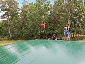 A trampoline in an outdoor setting surrounded by trees.