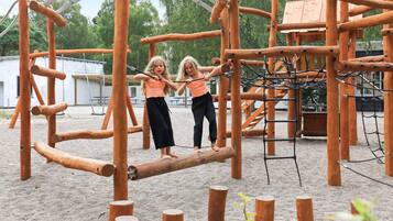 A playground with wooden climbing structures and a sandy ground.