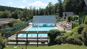 A swimming pool with a covered area, surrounded by greenery and a few buildings. - Holiday Apartment "pohlberg" (Annaberg-Buchholz)