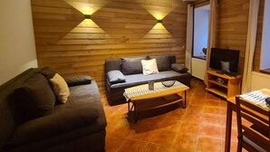 A cozy living room with a sofa, a coffee table, and a TV stand. - Holiday Apartment "pohlberg" (Annaberg-Buchholz)