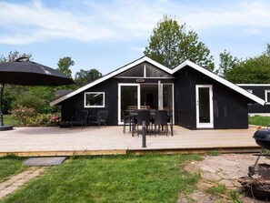 A modern black building with a wooden deck, outdoor seating, and a large umbrella.