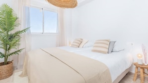 A bedroom with a large bed, a hanging light fixture, a potted plant, and a window with curtains. - Penthouse With Terrace and sea Views (Casares)