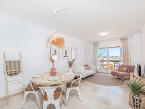 A modern living room with a round dining table, white chairs, a sofa, and a balcony with a view. - Penthouse With Terrace and sea Views (Casares)