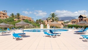 A poolside area with lounge chairs, a swimming pool, and buildings in the background. - Penthouse With Terrace and sea Views (Casares)
